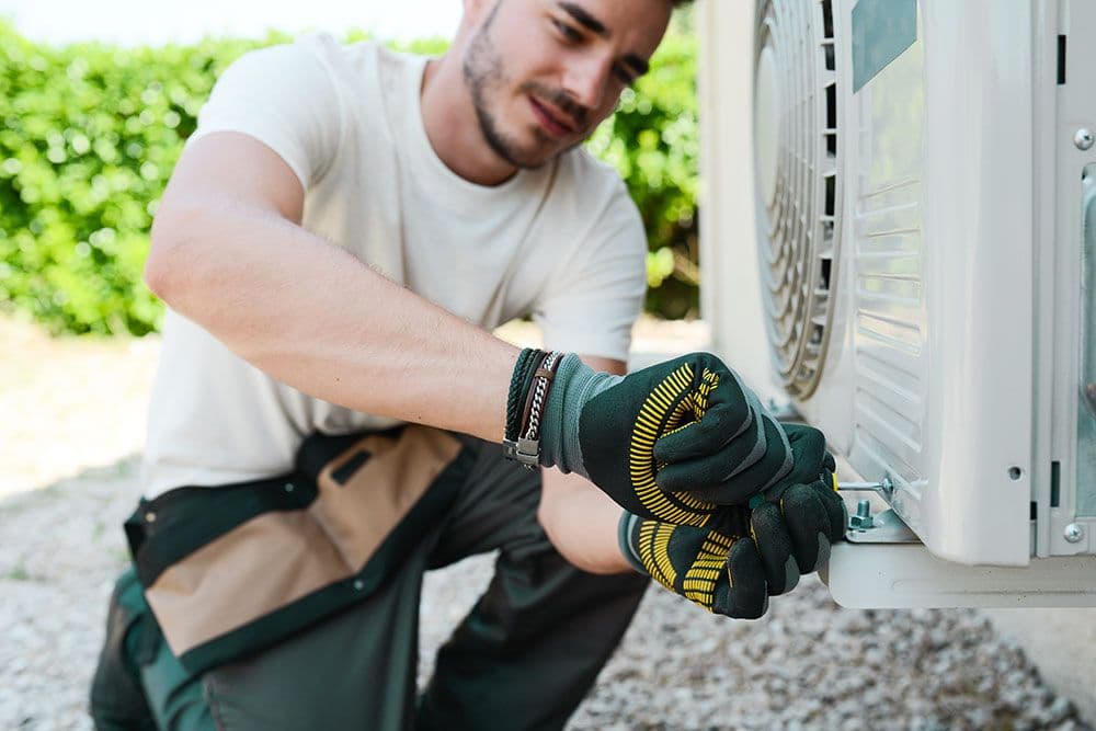 Installatör installerar luftvärmepump på husvägg