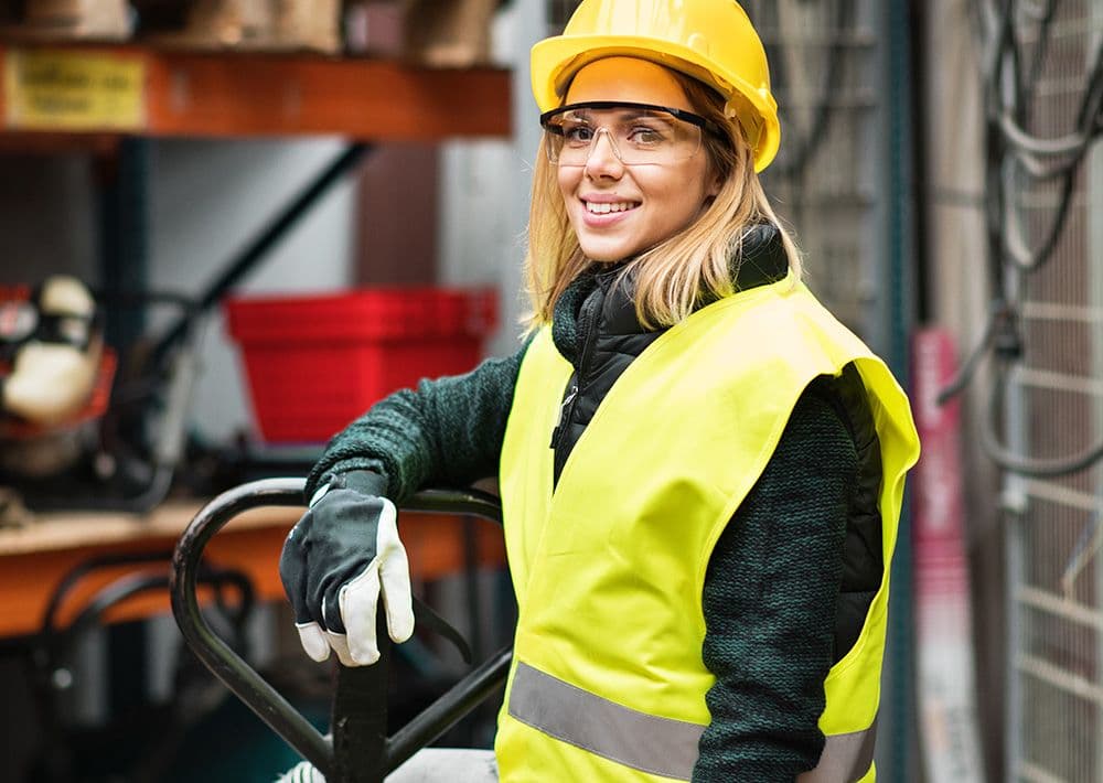 Kvinnlig entreprenör i gul väst inom transport lutar sig mot truck 