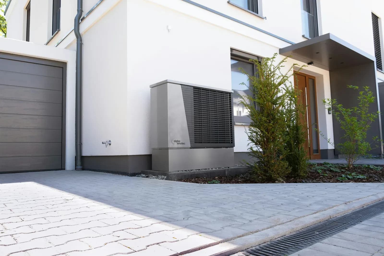 Luft/vattenvärmepump utomhus vid en modern villa · Foto: alpha innotec / Unsplash