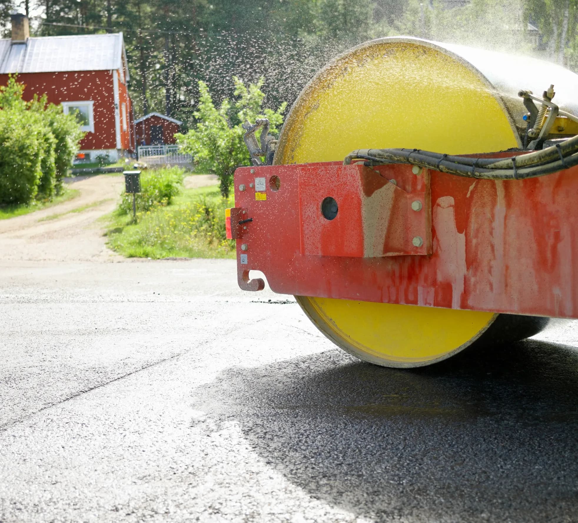 Asfaltering av väg framför hus en het sommardag