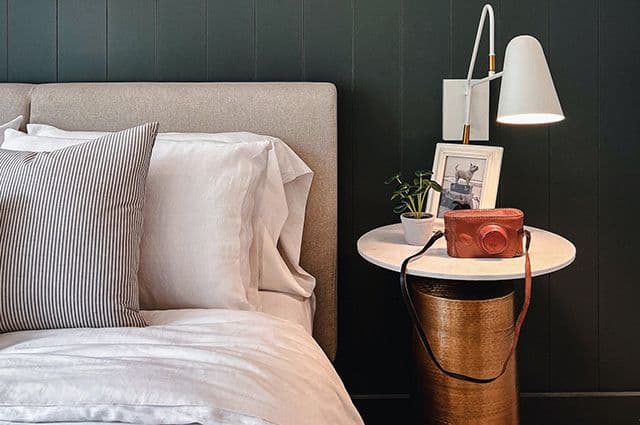 Sovrum med sänglampa med mörkblå träpanel och beige sänggavel