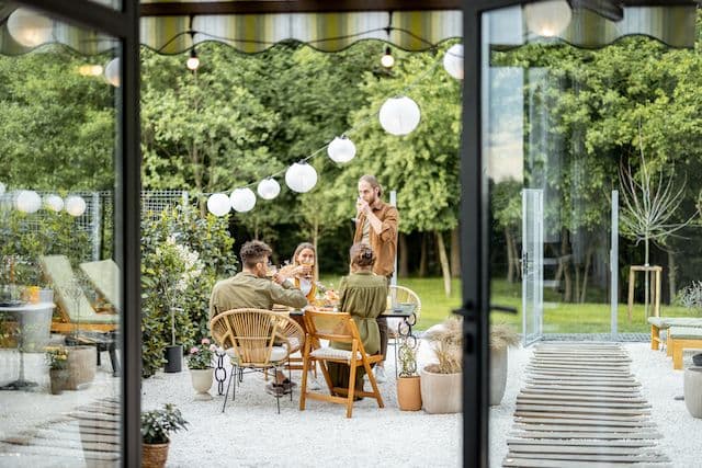 Uteplats med människor som sitter i en trädgård, lampor hänger ovanför