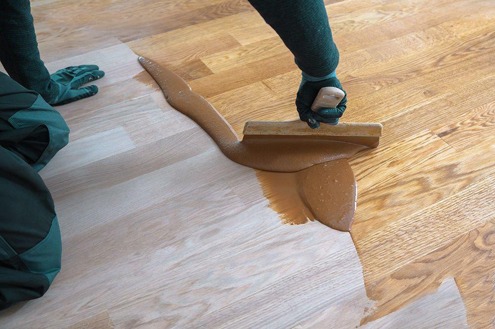 Hantverkare lackar golv för hand med spatel