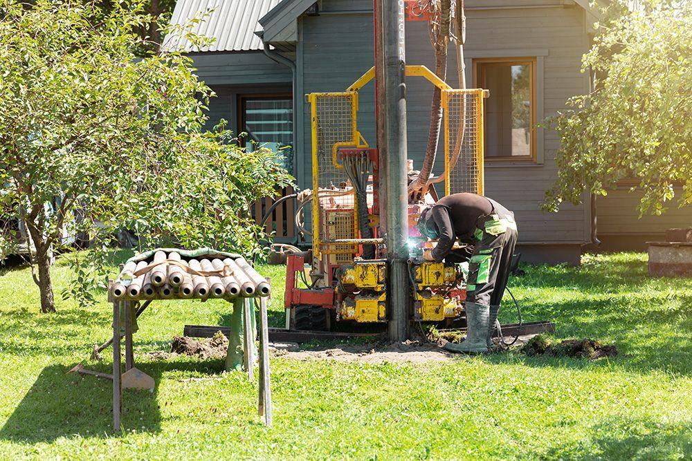 Arbetare borrar hål för bergvärme i trädgård