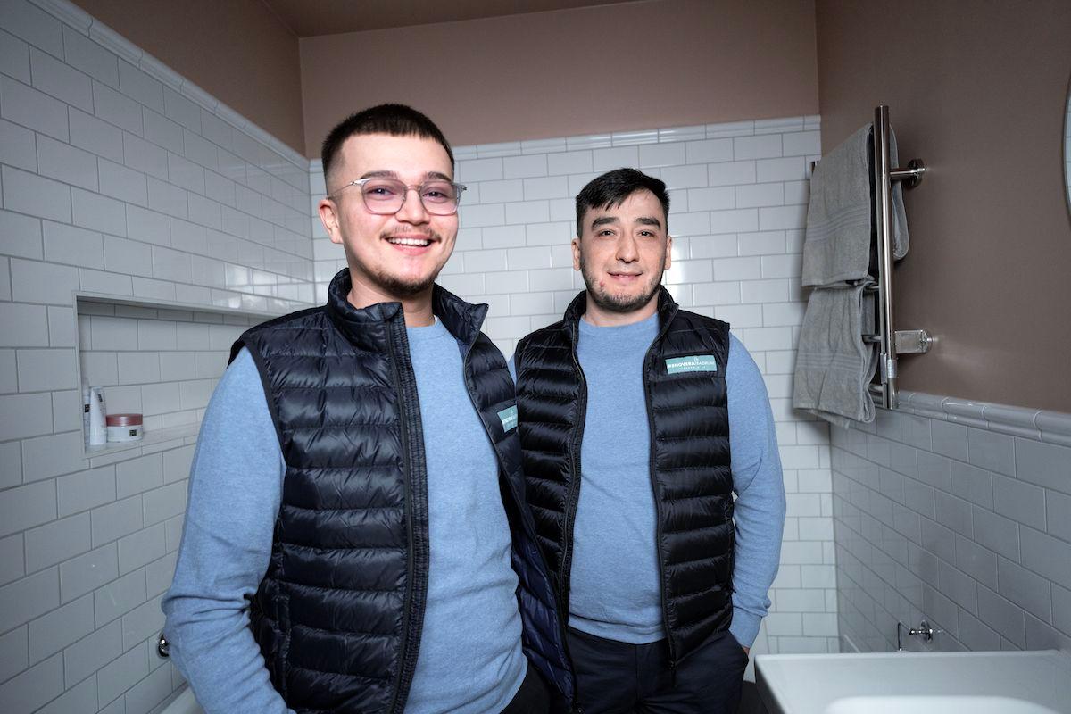 Två killar från företaget Renovera Badrum STHLM. De står i ett nytt, fräscht badrum som de har renoverat.