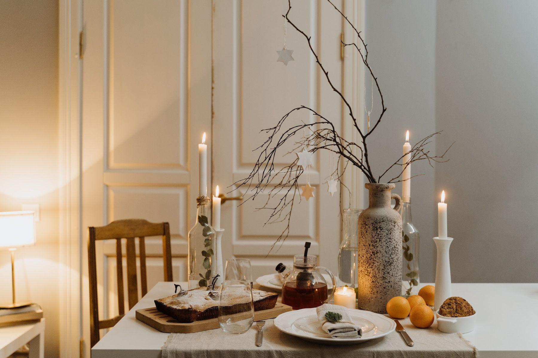 Ett dukat bord med julkänsla i ett nystädat hem. Levande ljus, glögg och mjuk pepparkaka.