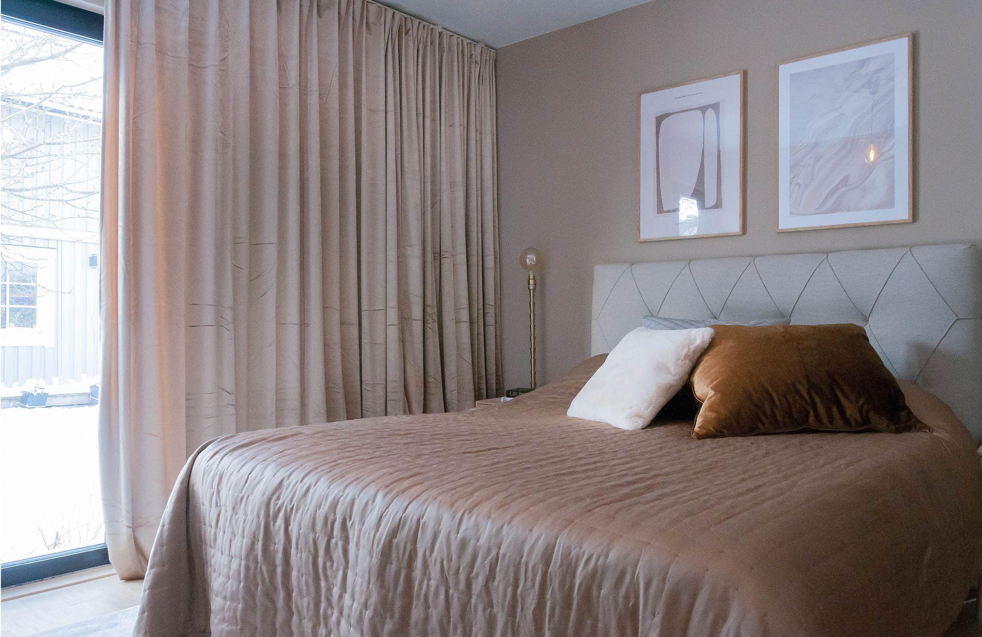 Efterbild av renovering sovrum i hus, säng med ljust överkast, sänggavel i grått, ljusa gardiner