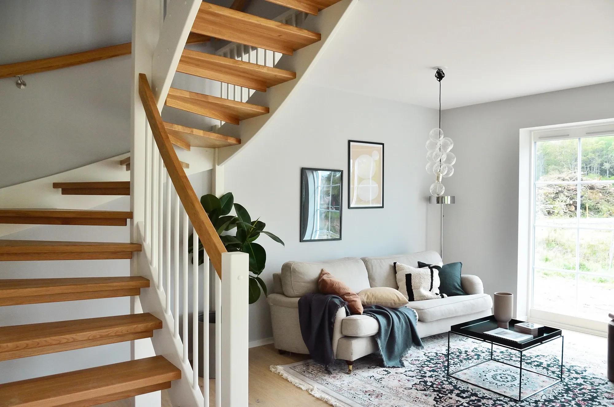 Miljöbild på vardagsrum med modern skandinavisk inredning där trapprenovering av trätrappa utförts av erfarna hantverkare