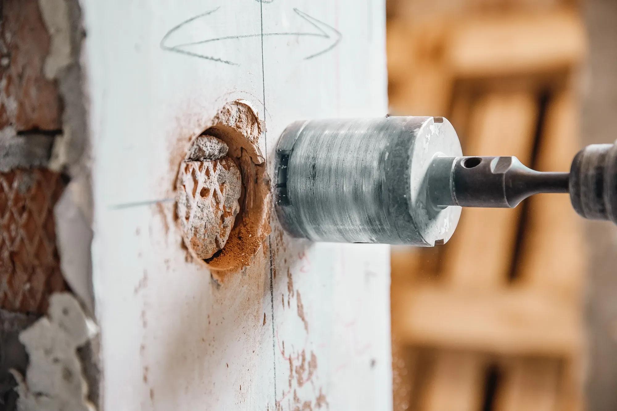 Erfarna byggarbetare utför precisionshåltagning i betongvägg med pneumatisk hammare och diamantkrona - Professionell håltagning för ditt byggprojekt