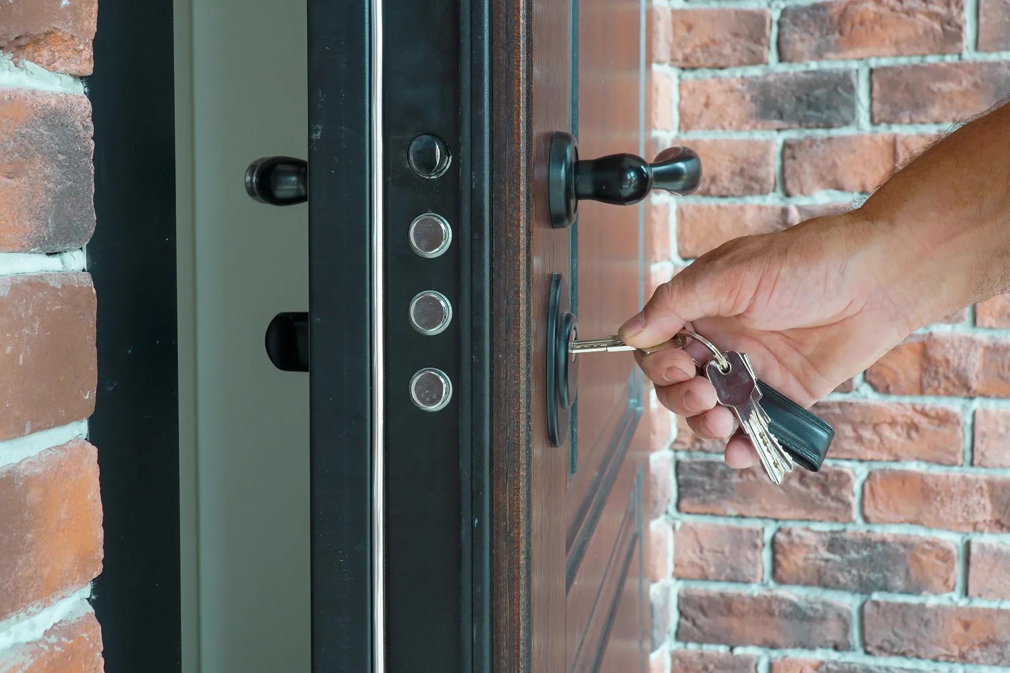 Närbild på hand som låser upp dörr med tegelvägg i bakgrunden - Säker och smidig låsöppning för ditt hem