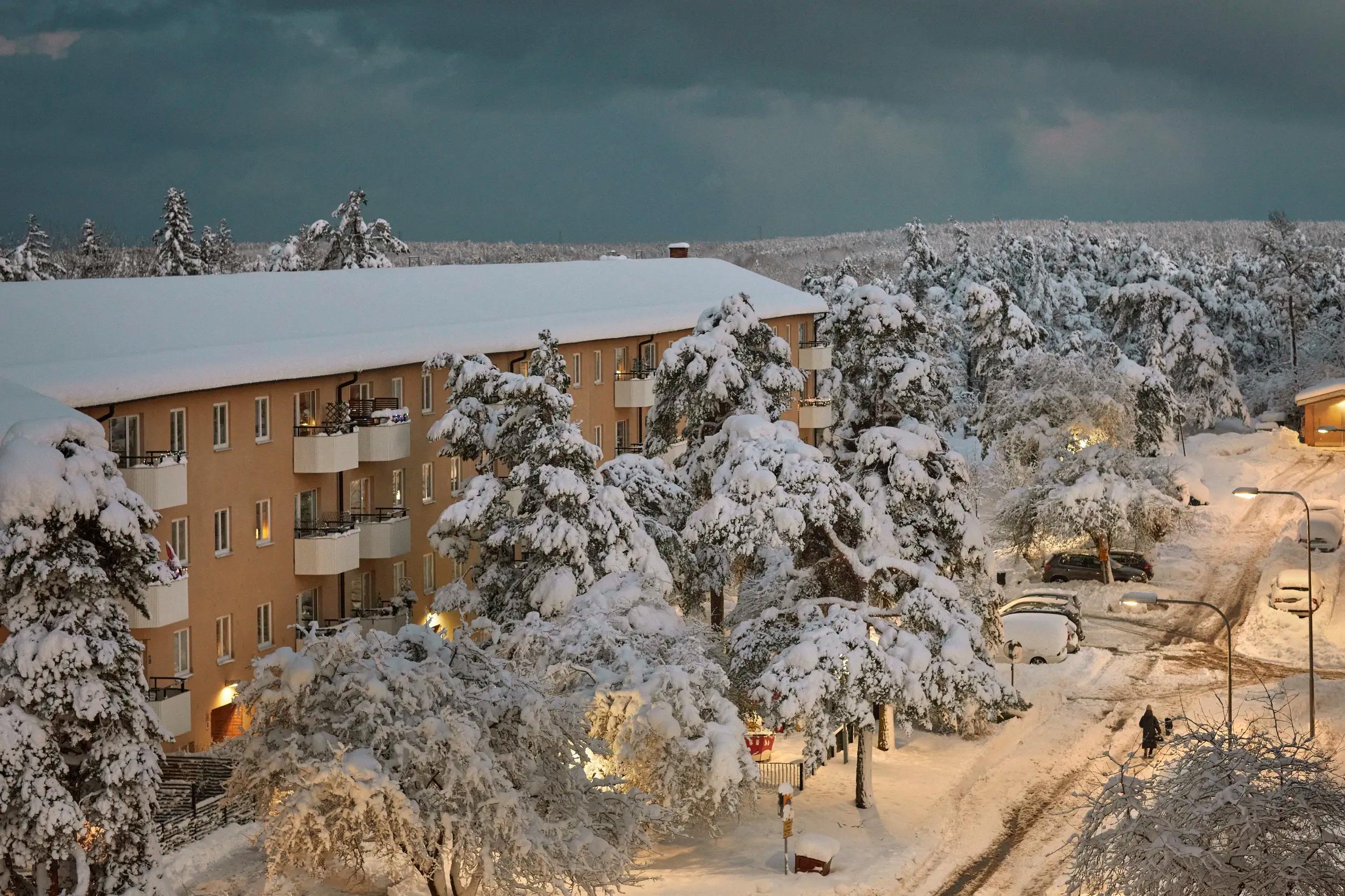 Vinterlandskap med täckt snö och lägenhetsbyggnader - representerar Offerta.se's snöröjnings- och isborttagningstjänst för effektiv och pålitlig hantering av vinterväde
