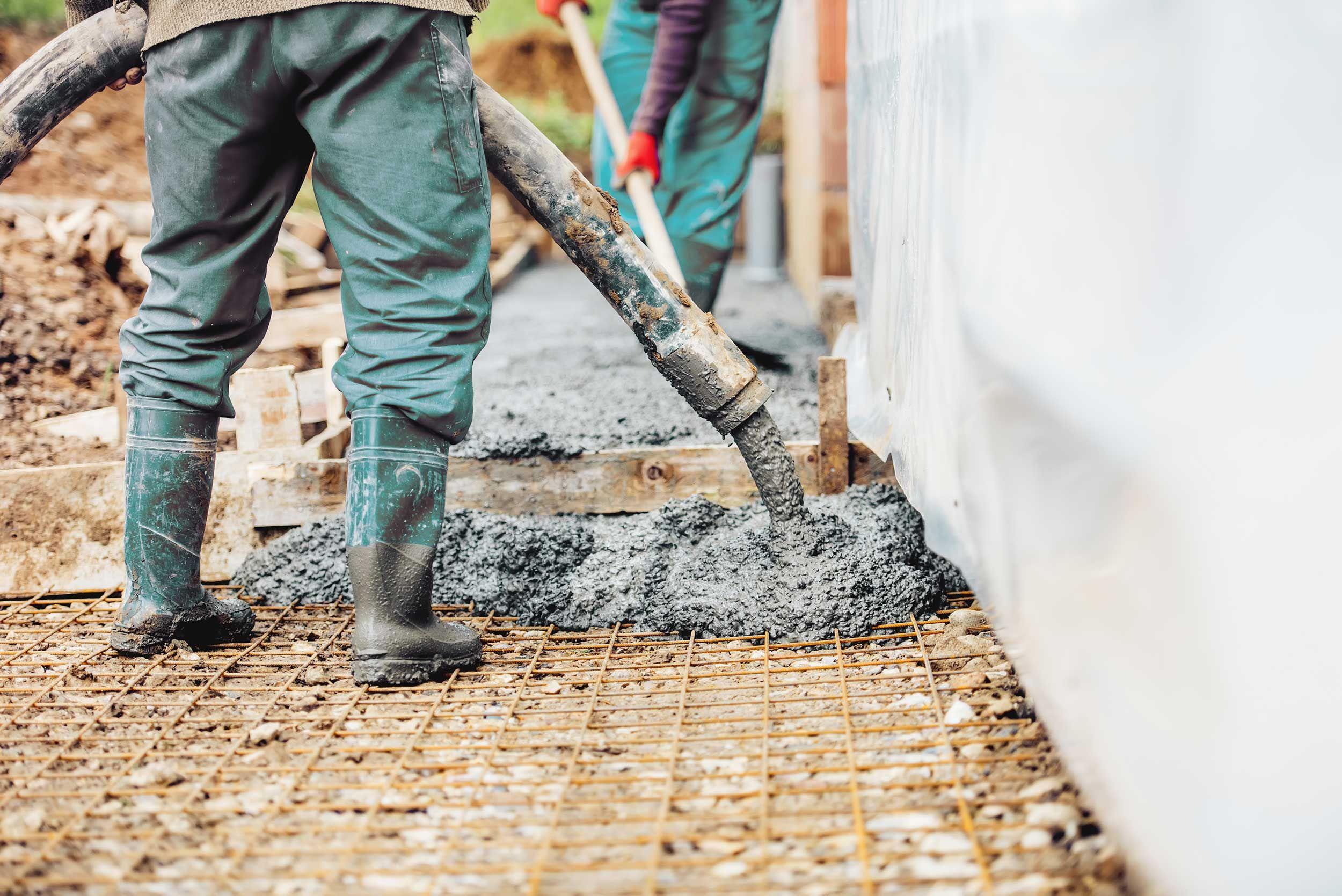 Arbetare lägger cement eller betong med automatisk pump