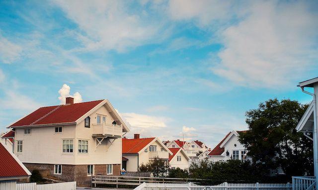 Flera vita hus med röda tak i ett villaområde i Sverige. Ovanför husen är en blå himmel.