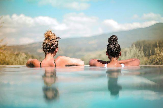 Två kvinnor badar i en pool och ser ut över horisonten