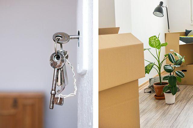 Närbild på nycklar i dörr och flyttkartonger och växter i lägenhet inför flytt
