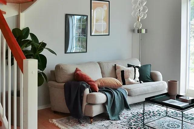 Skandivasiskt inredning i vardagsrum med beige soffa och mörkgröna kuddar