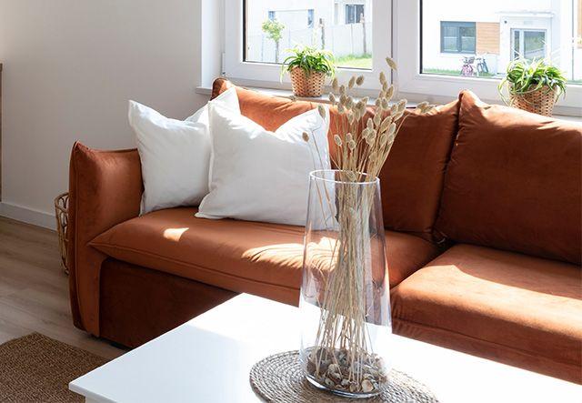 Vårstädad lägenhet med rostbrun soffa sol som sipprar genom fönster