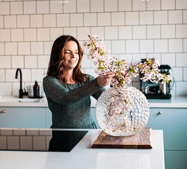 Kvinna sätter blommor i en vas i sitt nyrenoverade kök