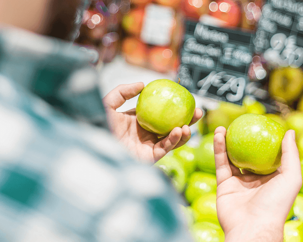 Närbild på händer som håller i och jämför äpplen