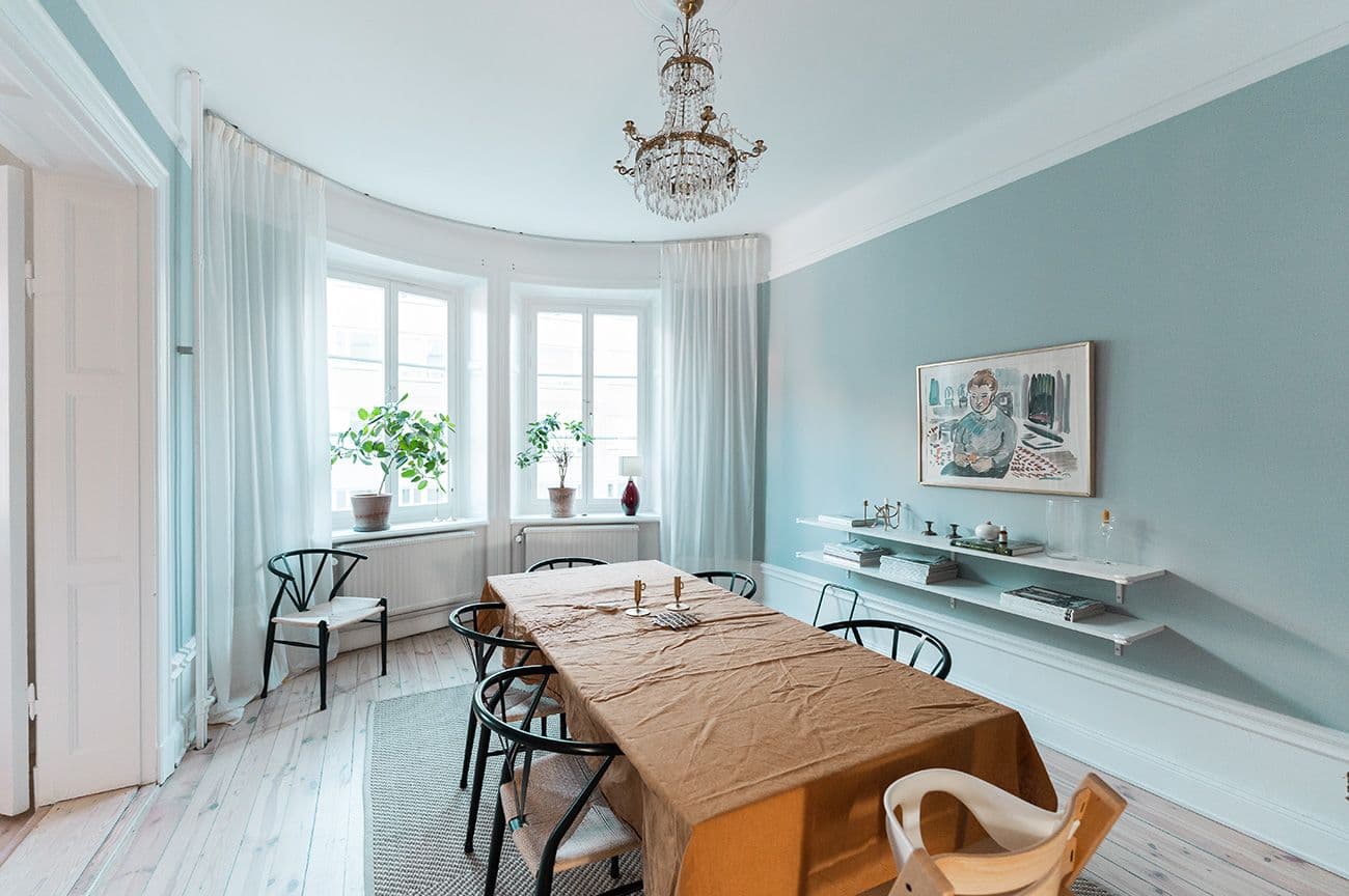 Totalrenovering av sekelskiftslägenhet med ljusblågrönt vardagsrum med ljusblå kakelugn