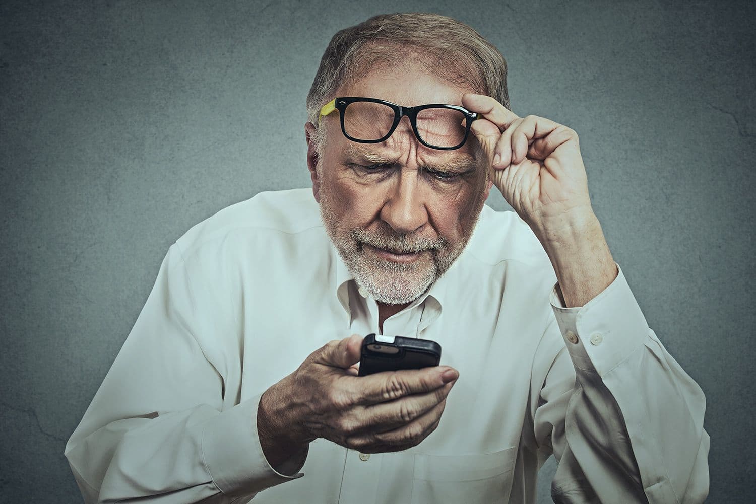 Senior arbetare kollar på mobilen och ser fundersam ut