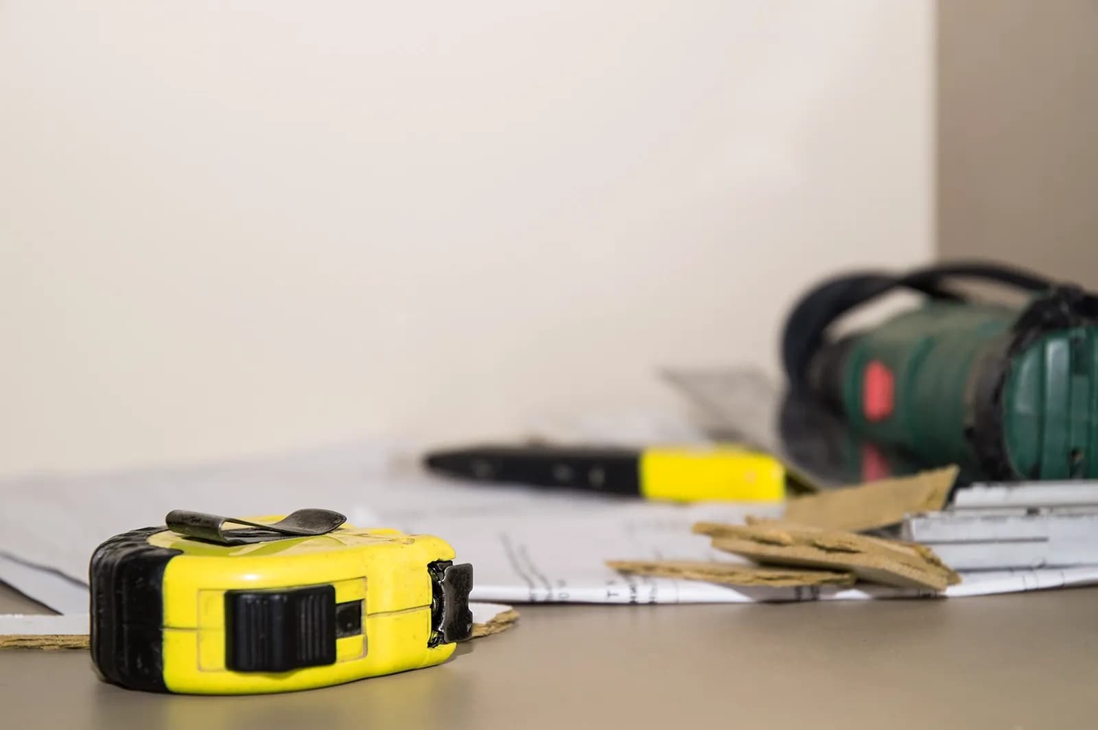 Måttband och arbetskniv ligger ovanpå pappersdokument