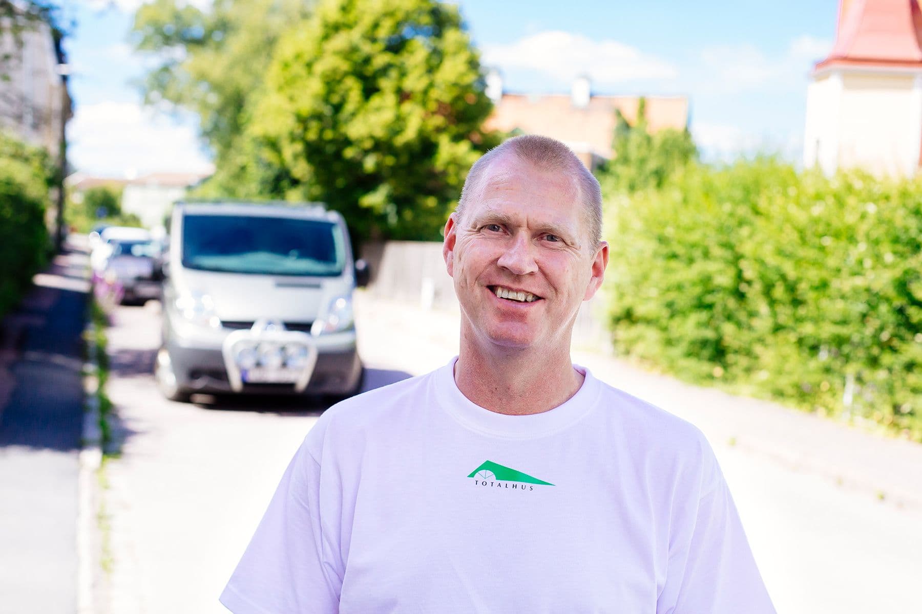 Porträtt på Niklas Björkholm från Totalhus står på en gata en sommardag