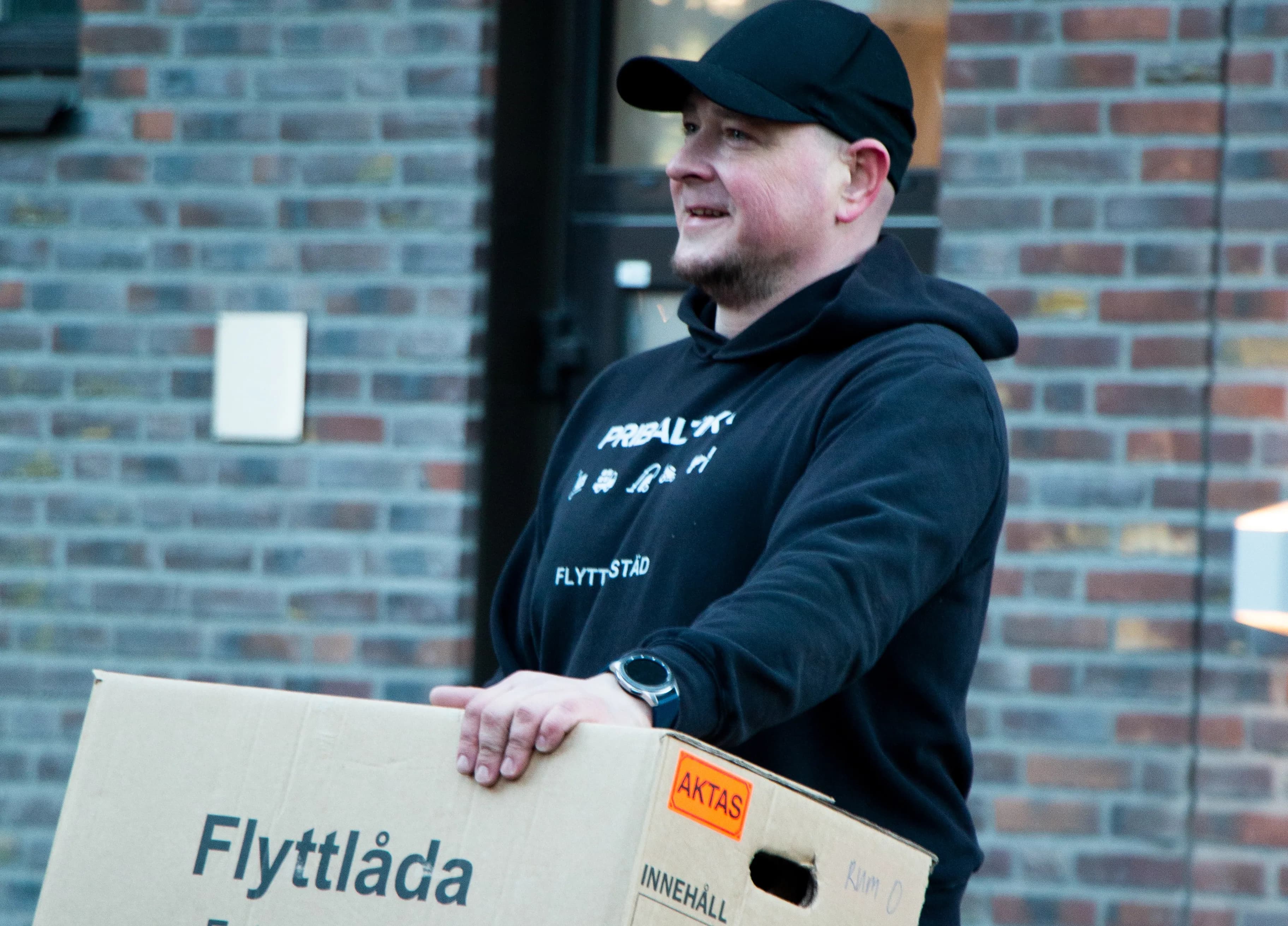 Medarbetare från Pribaltika lyfter flyttlådor framför en flyttbil