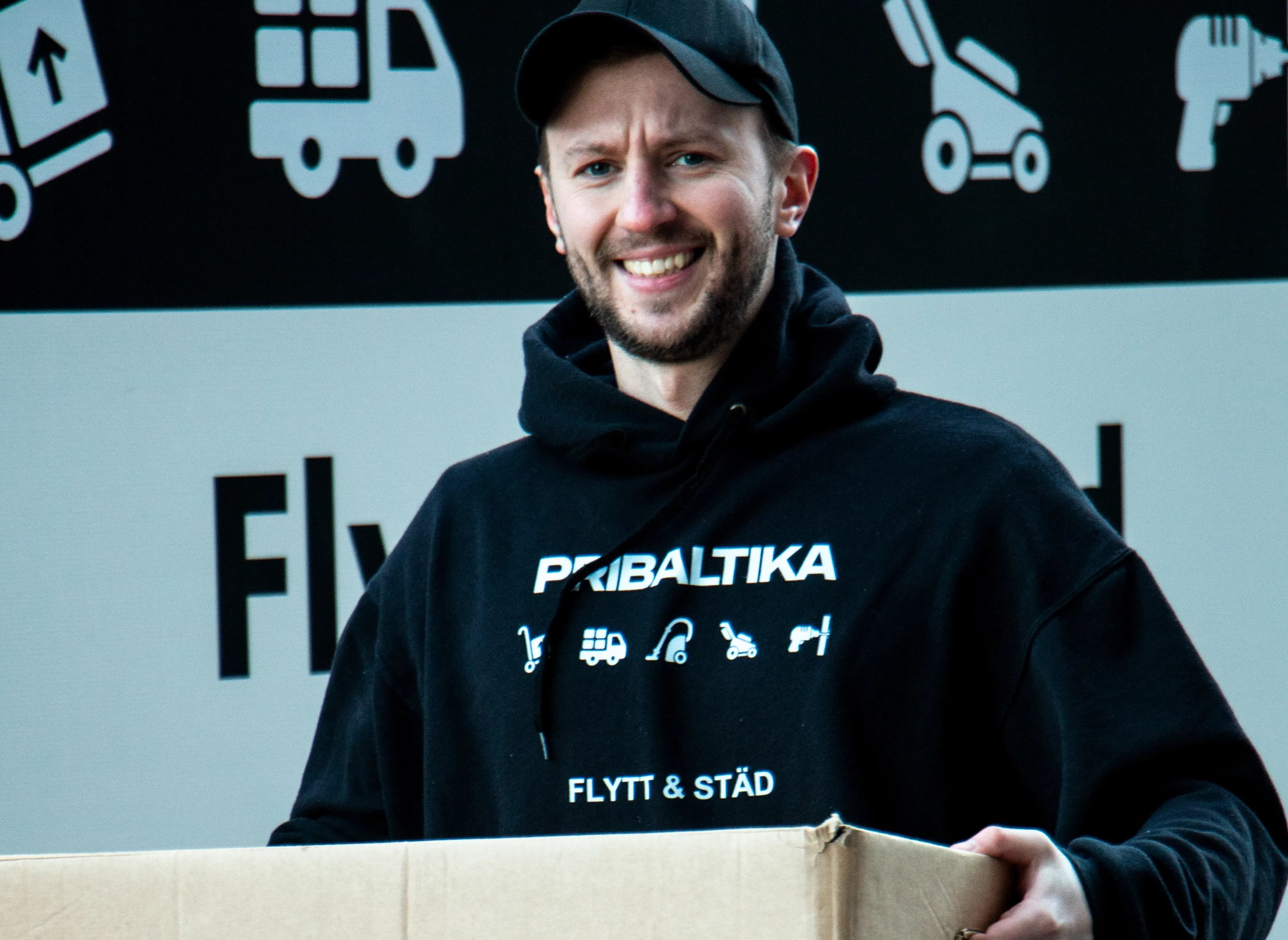 En medarbetare från Pribaltika lyfter flyttlådor framför en flyttbil
