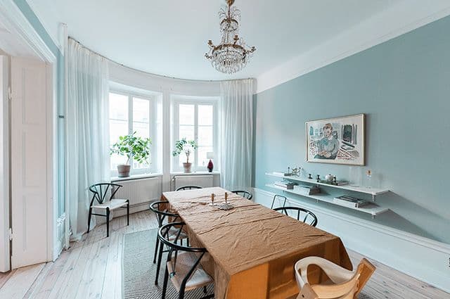 Totalrenovering av sekelskiftslägenhet med ljusblågrönt vardagsrum med ljusblå kakelugn