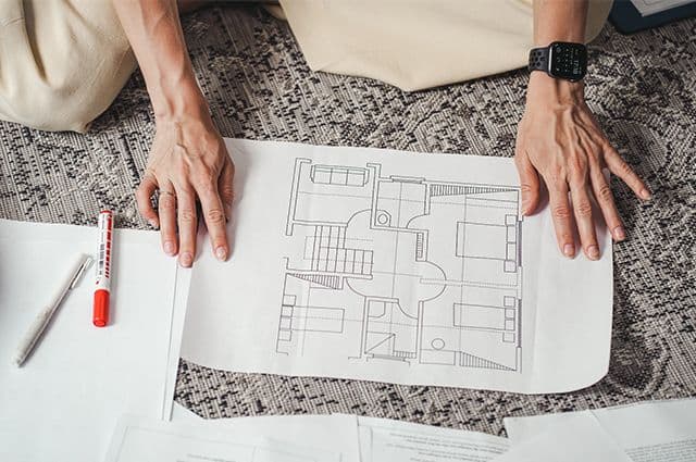 Två händer som visar en arkitektritning
