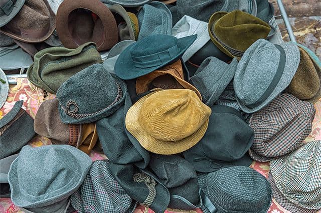 Massor av olika hattar på hög visualiserar att ha på sig många hattar på jobbet