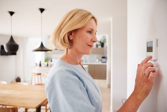 Kvinna kollar värmepanel i hus